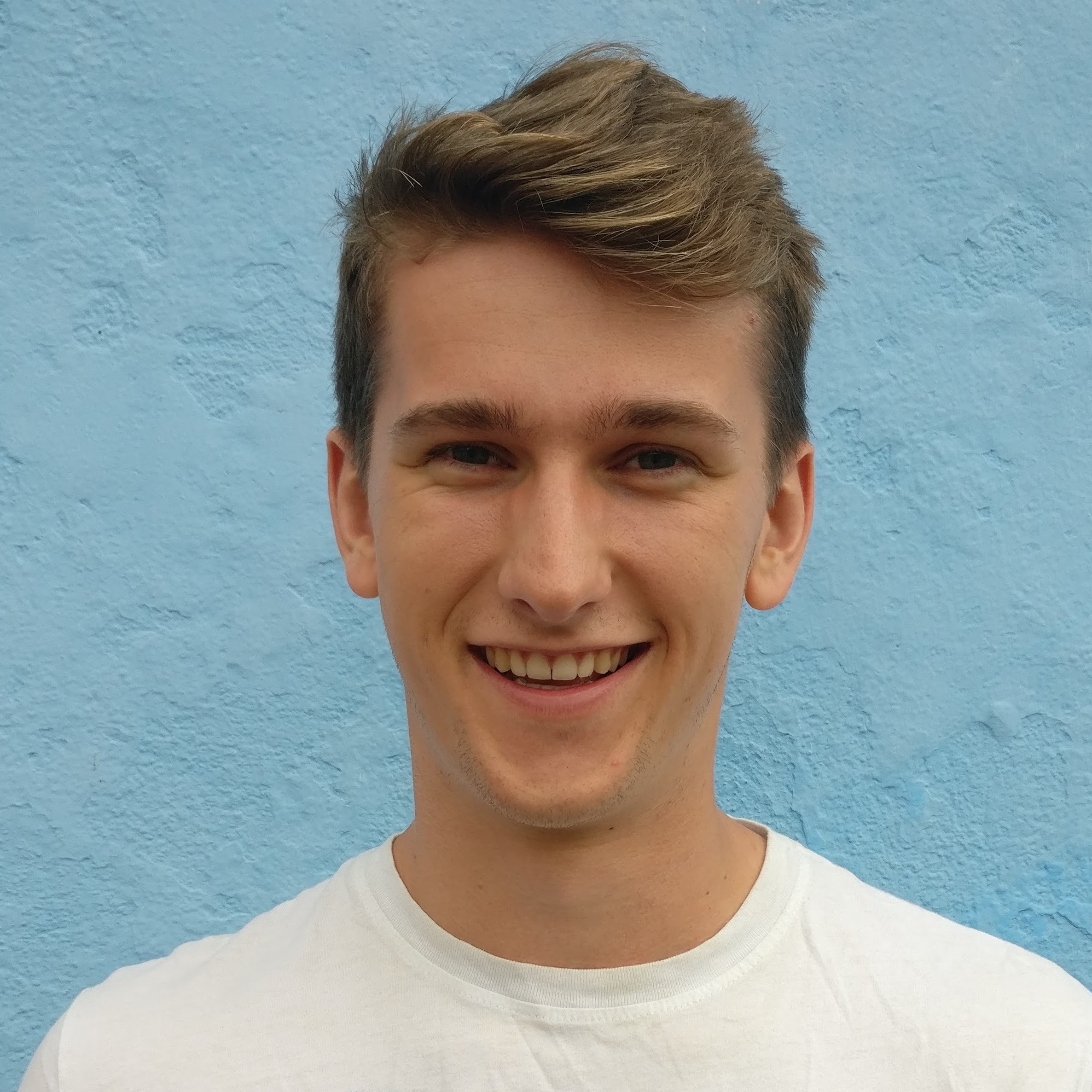 headshot of Luke looking happy with a blue background